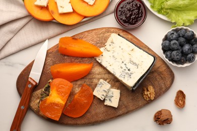 Delicious persimmon with blue cheese on white table, flat lay