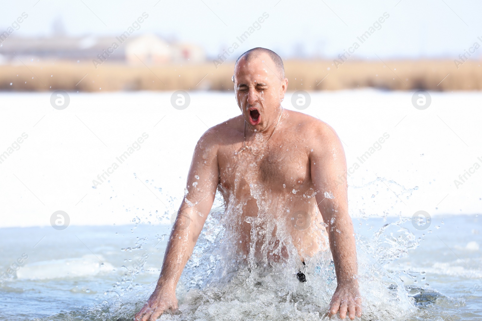 Photo of MYKOLAIV, UKRAINE - JANUARY 19, 2021: Man immersing in icy water on winter day. Traditional Baptism ritual