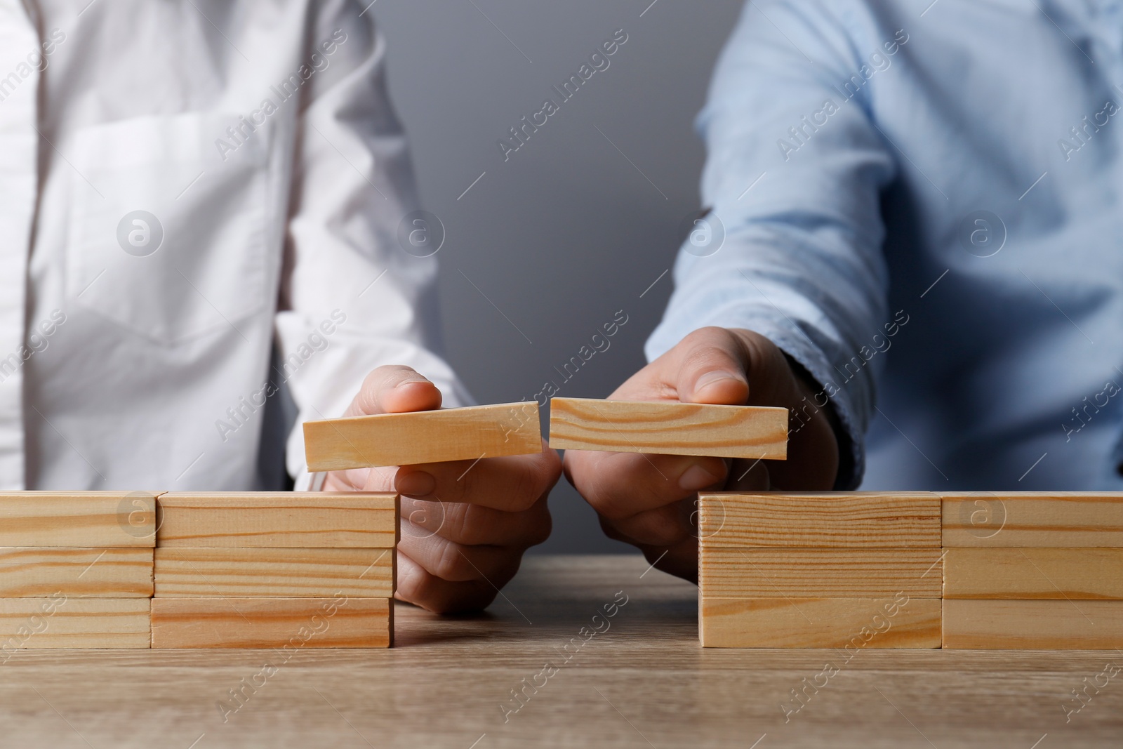 Photo of Businesspeople building bridge with wooden blocks at table, closeup. Connection, relationships and deal concept