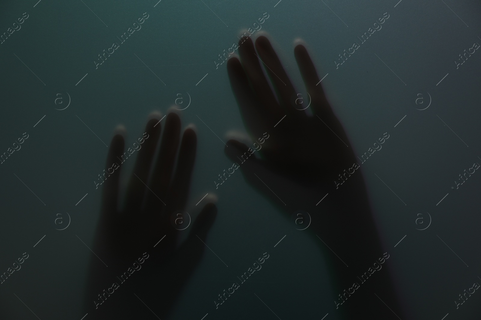 Photo of Silhouette of creepy ghost behind glass against color background, closeup