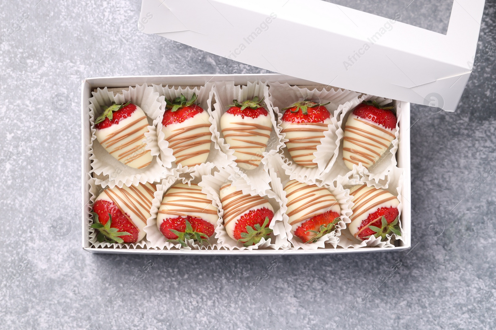 Photo of Box with delicious chocolate covered strawberries on light grey table, top view