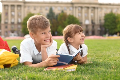 Photo of Children with stationery doing school assignment on grass outdoors