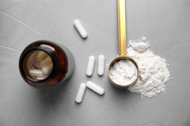 Photo of Amino acid pills and powder on grey table, flat lay