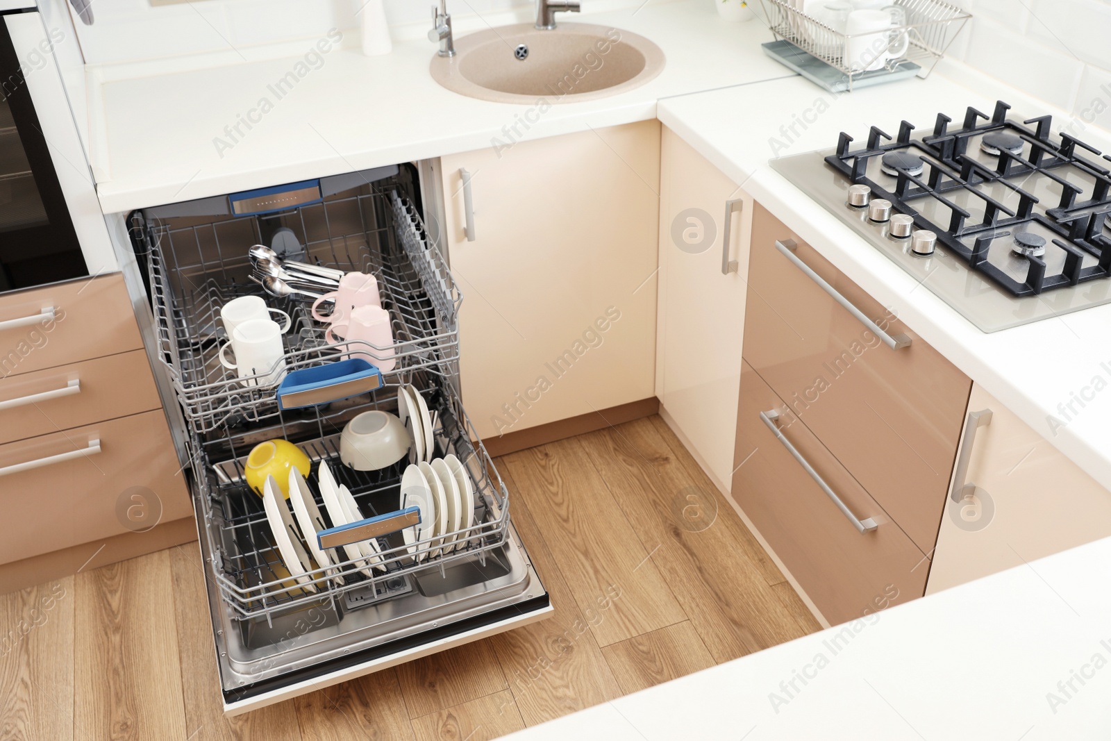 Photo of Open dishwasher with clean tableware in kitchen