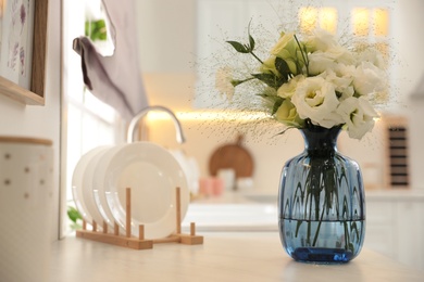 Photo of Bouquet of beautiful eustoma flowers on white countertop in kitchen. Interior design