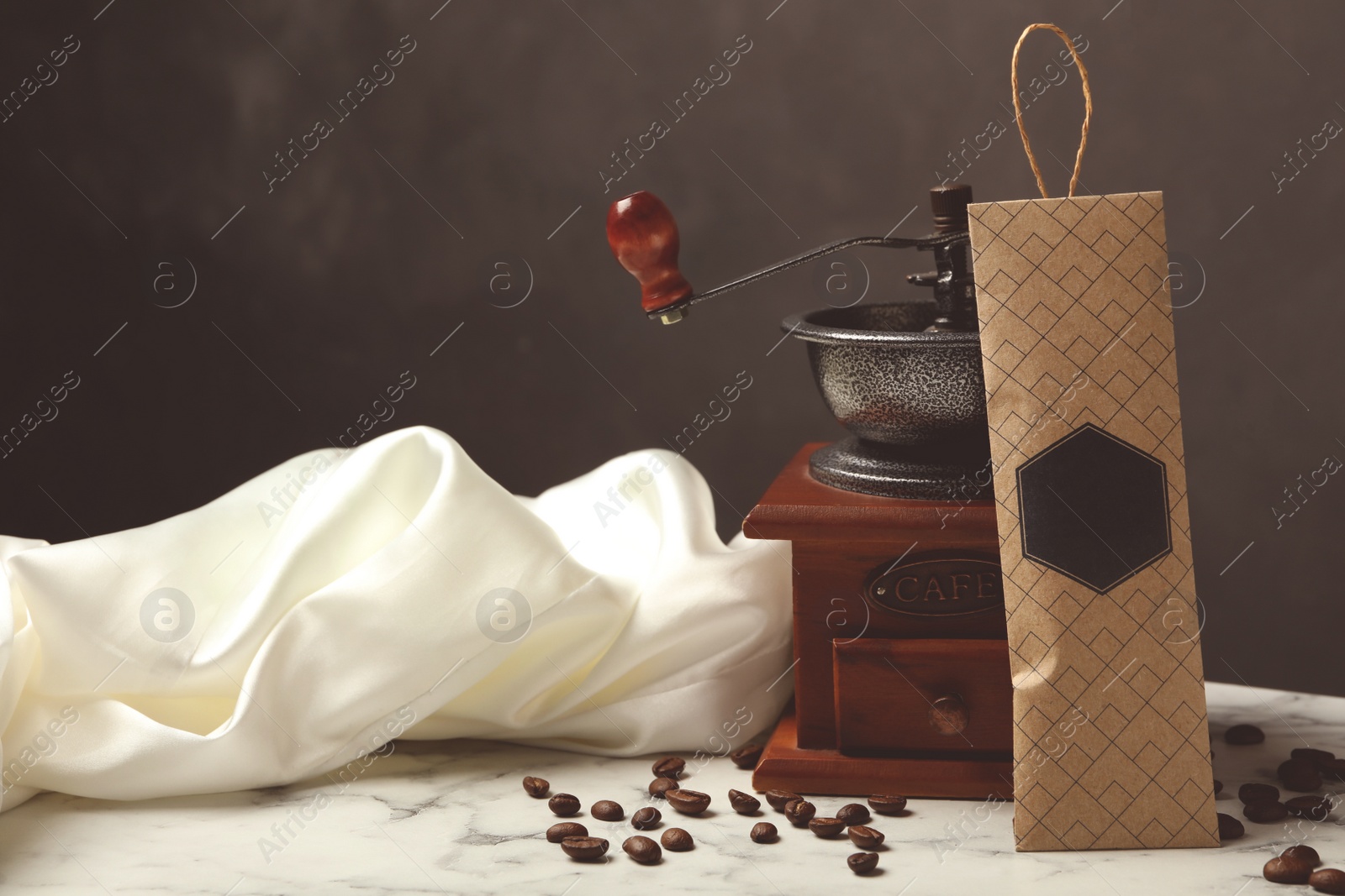 Photo of Scented sachet, coffee grinder and beans on white marble table against black background, space for text