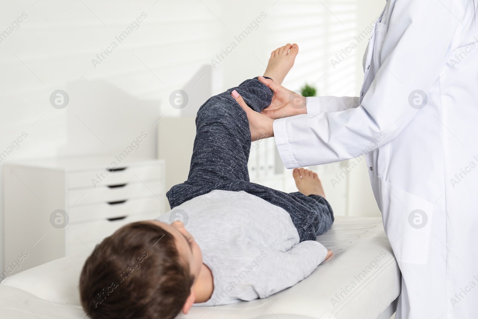 Photo of Professional orthopedist examining little patient's leg in clinic