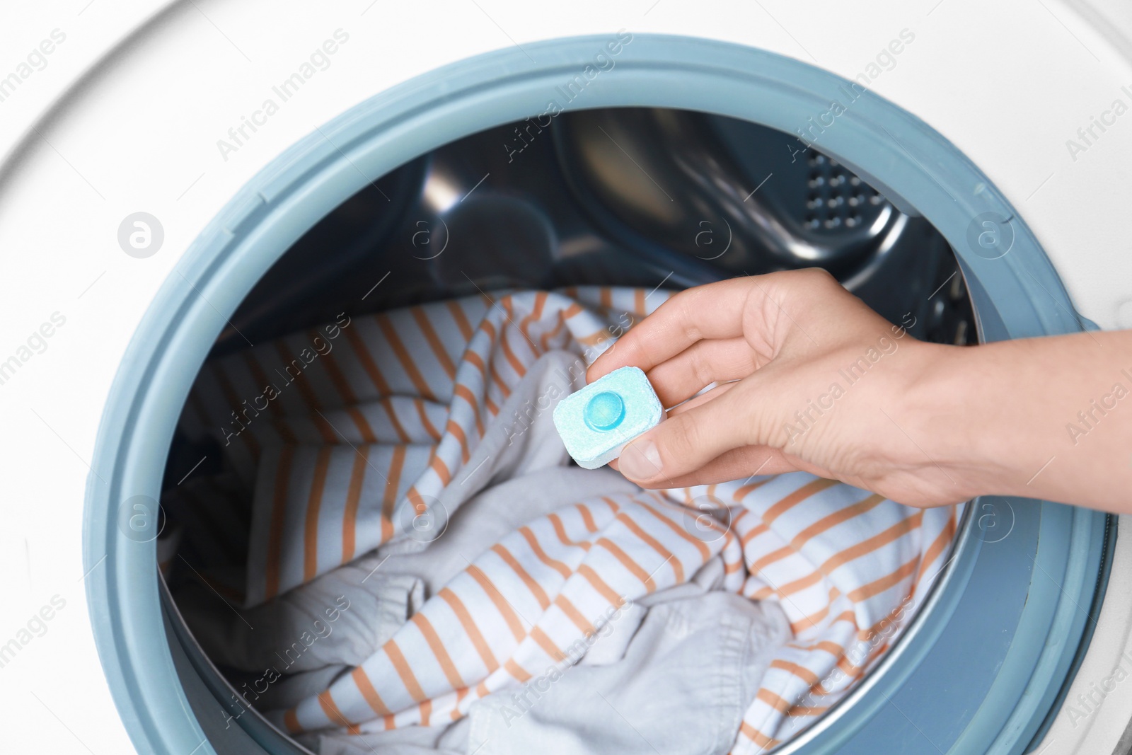 Photo of Woman putting water softener tablet into washing machine, closeup