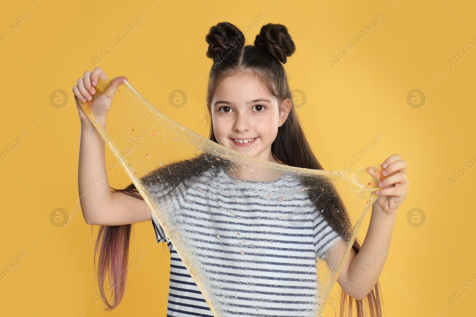 Photo of Little girl with slime on yellow background