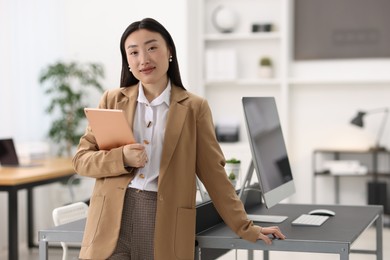 Portrait of beautiful businesswoman with tablet in office. Space for text