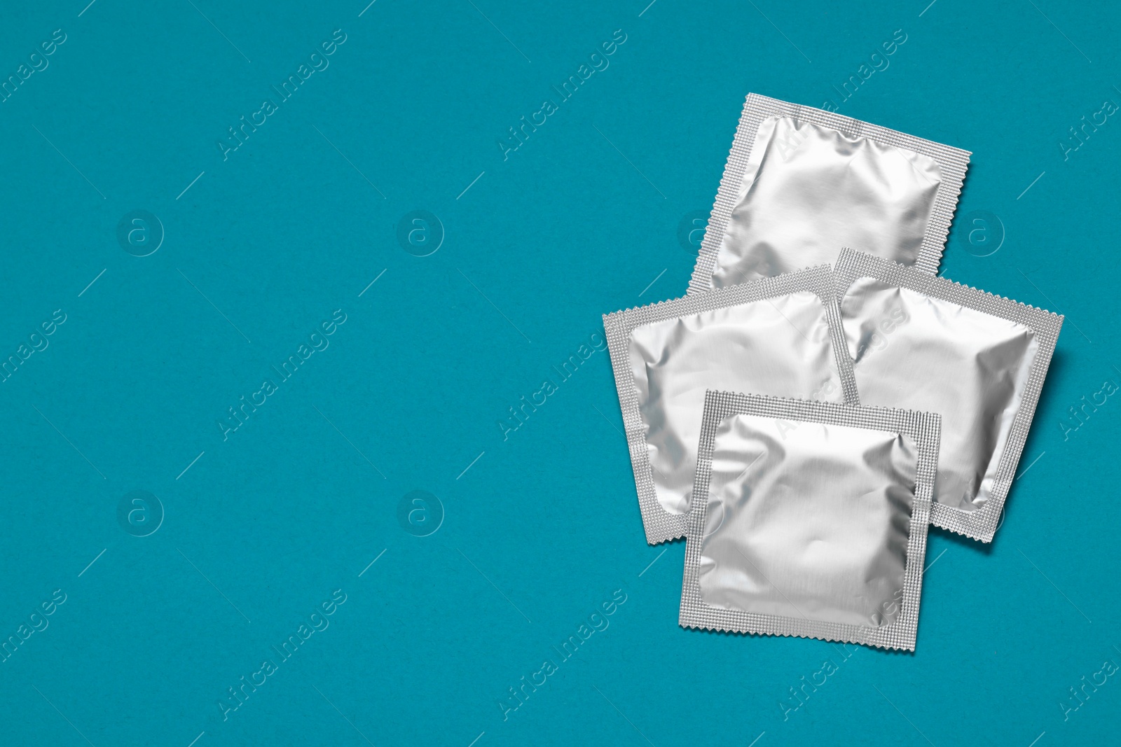 Photo of Packaged condoms on light blue background, top view with space for text. Safe sex