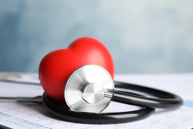 Photo of Stethoscope, red heart and cardiogram on table. Cardiology concept