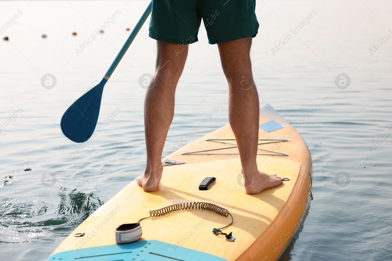 Photo of Man paddle boarding on SUP board in sea, back view