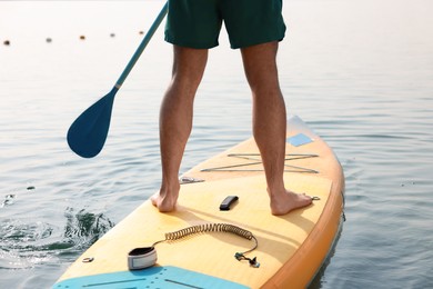 Photo of Man paddle boarding on SUP board in sea, back view
