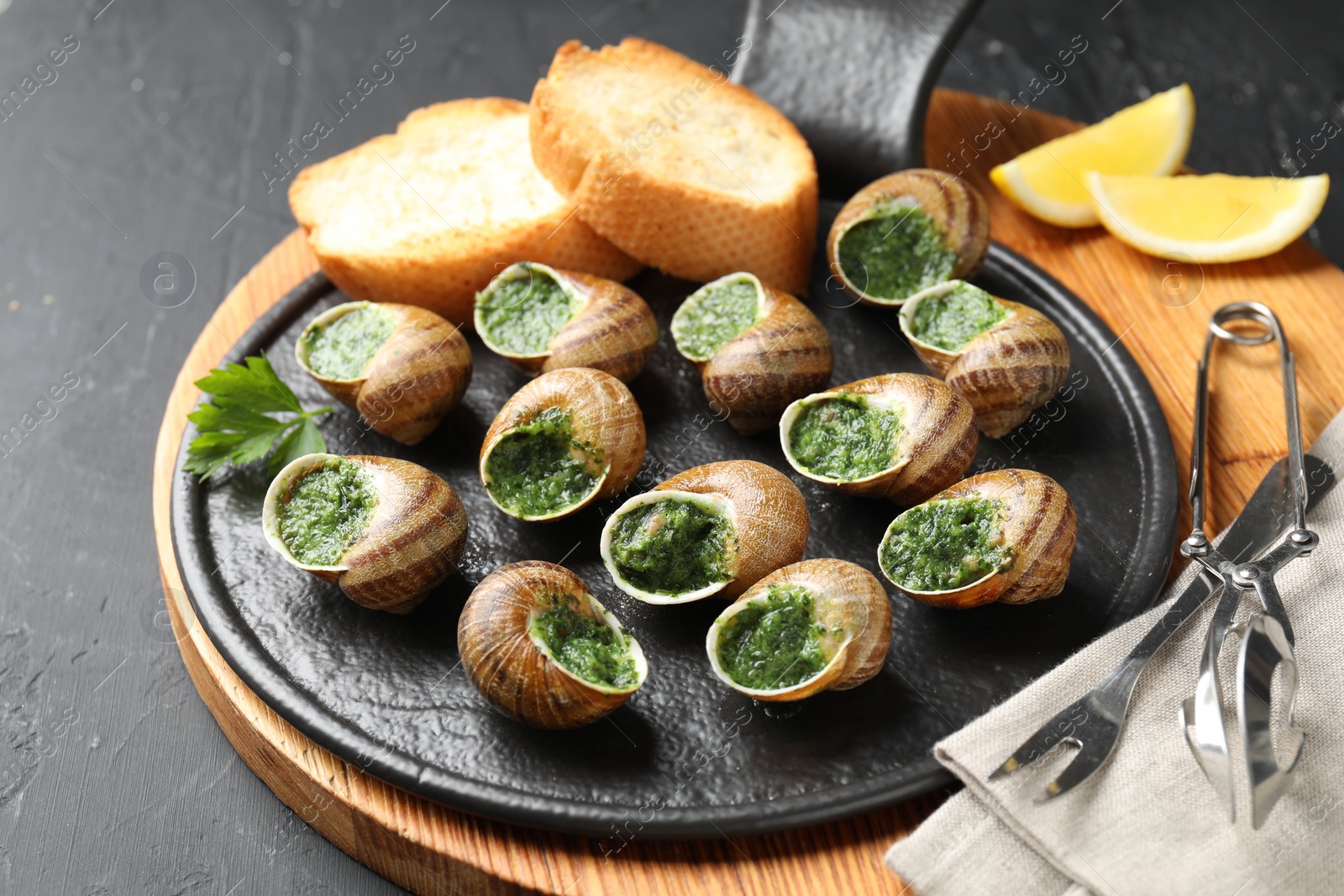 Photo of Delicious cooked snails served on grey textured table