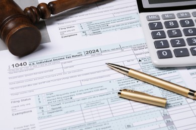 Photo of Tax return forms, gavel, calculator and pen on grey table, closeup