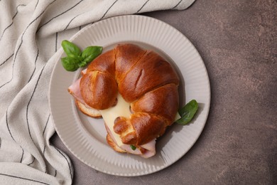 Photo of Tasty crescent roll with ham, cheese and basil on grey table, top view