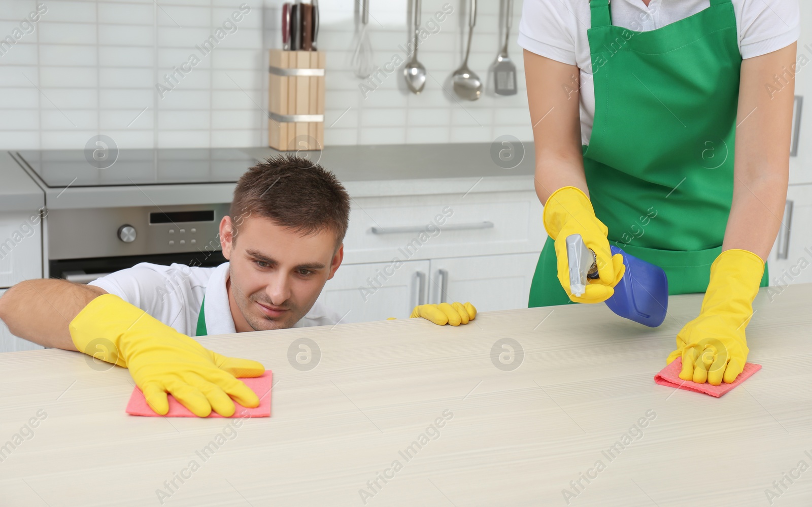 Photo of Team of janitors cleaning table in kitchen