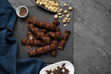 Photo of Tasty chocolate bars with nuts on black table, flat lay. Space for text