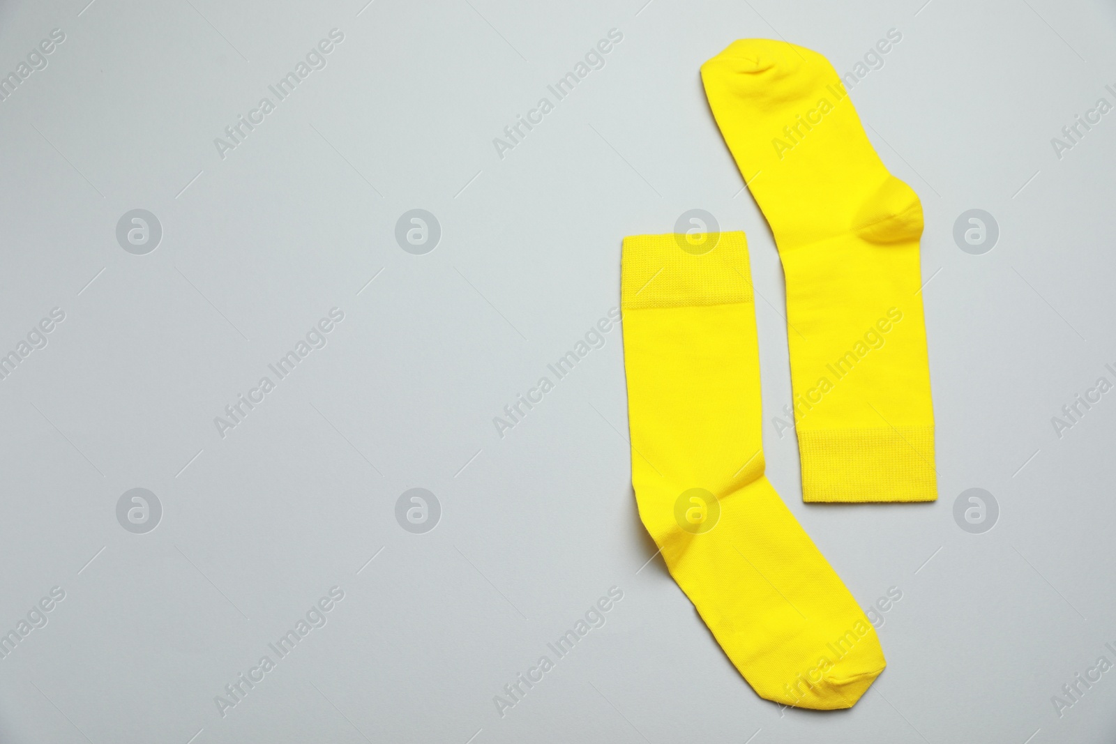 Photo of Yellow socks on light grey background, flat lay. Space for text