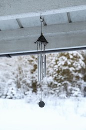 Photo of Stylish wind chimes hanging on winter day outdoors
