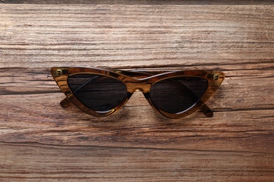 Photo of Stylish sunglasses on wooden background, top view