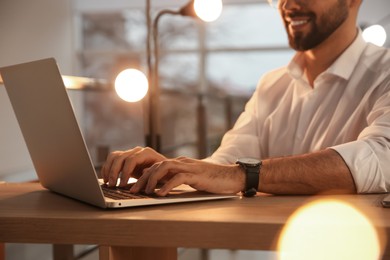 Man working with laptop at table in office, closeup