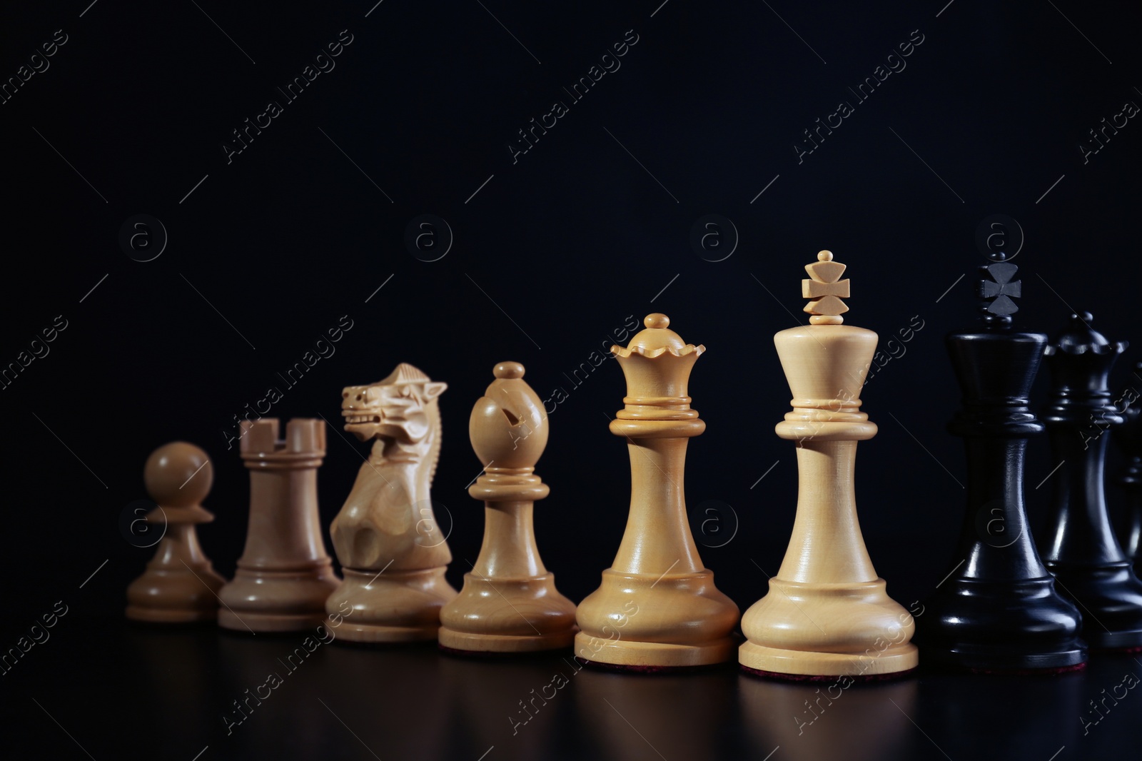 Photo of White and black chess pieces against dark background. Competition concept