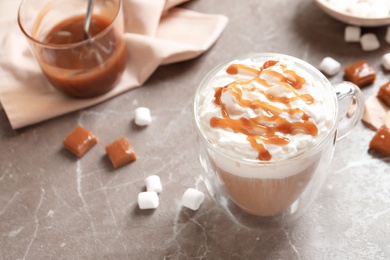 Cup of coffee with caramel topping on grey background