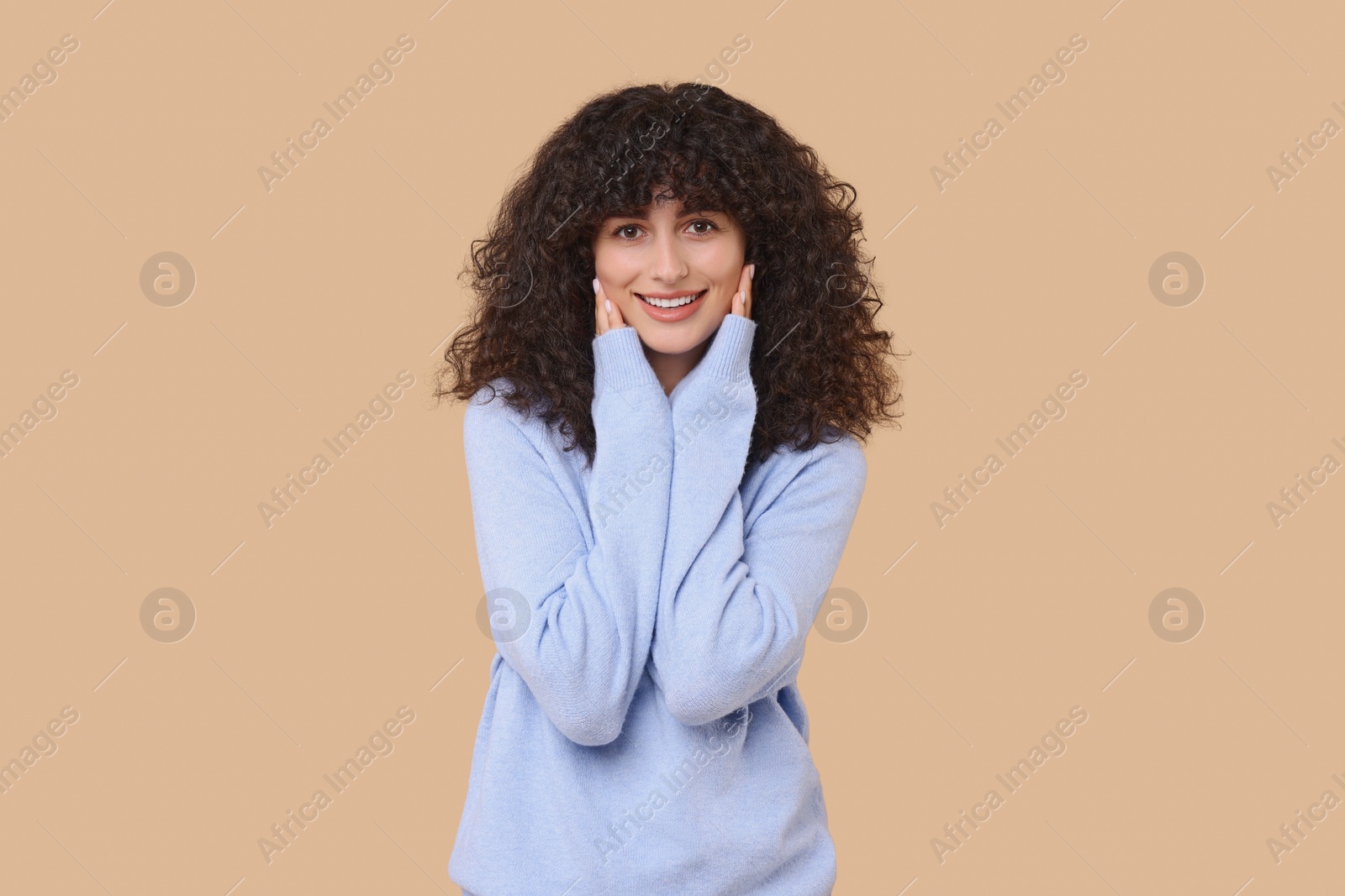 Photo of Happy young woman in stylish light blue sweater on beige background