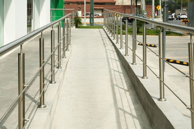 Concrete ramp with shiny metal railings outdoors