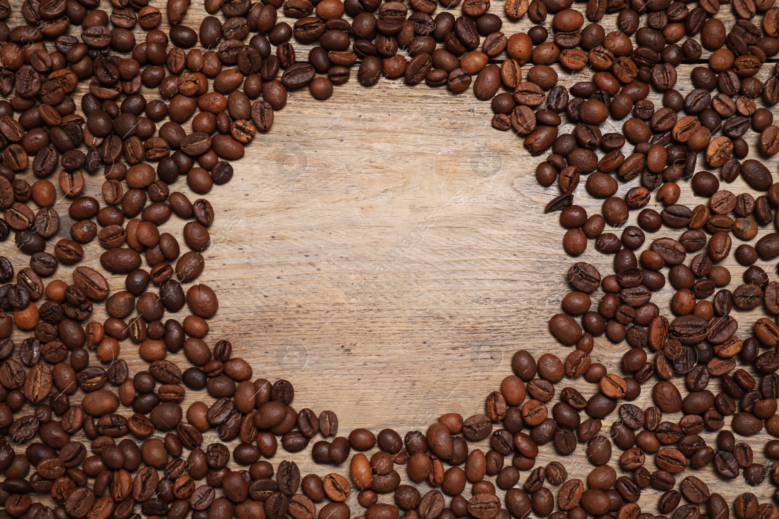 Photo of Frame made of roasted coffee beans on wooden table, flat lay. Space for text