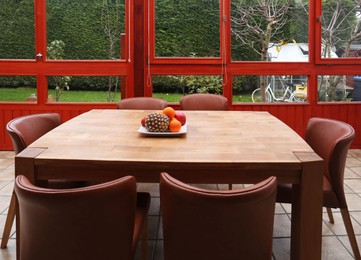 Wooden table with fruits and stylish chairs on terrace