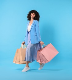 Photo of Happy young woman with shopping bags on light blue background