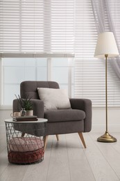 Photo of Comfortable place for rest with grey armchair near window indoors