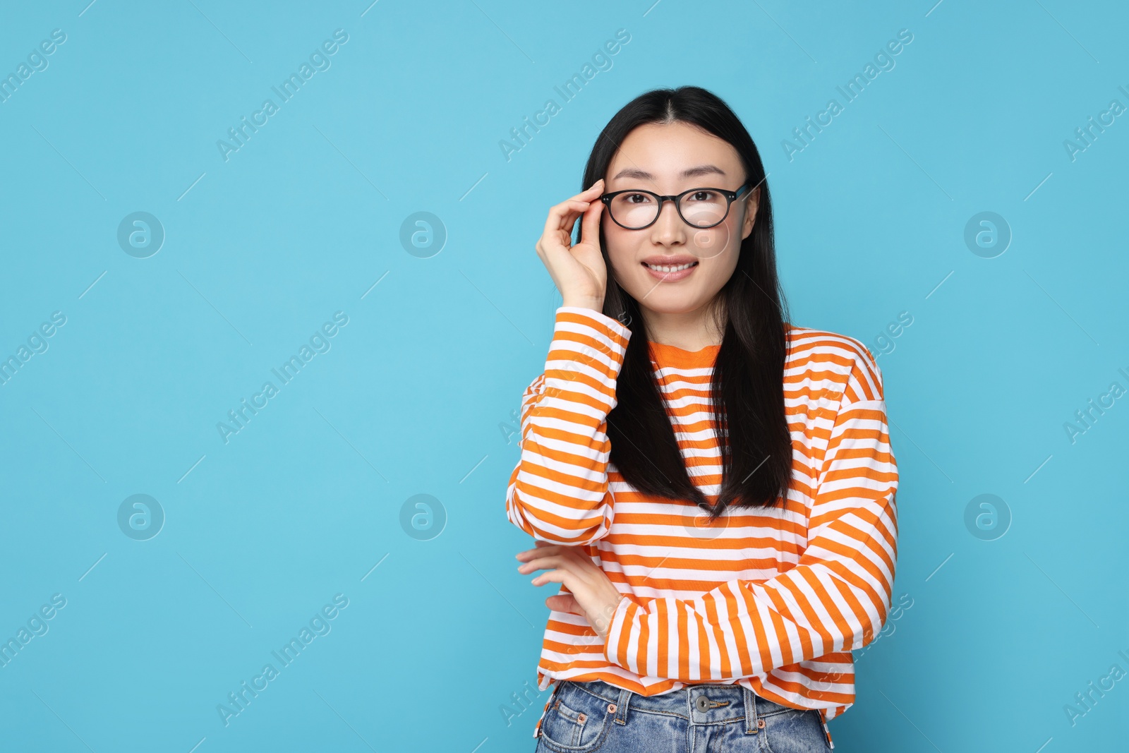 Photo of Portrait of happy woman in glasses on light blue background. Space for text