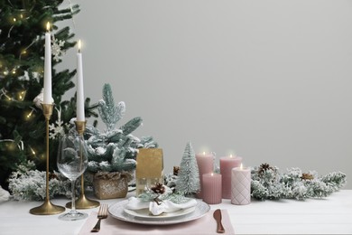 Photo of Festive place setting with beautiful dishware, cutlery and cone for Christmas dinner on white wooden table. Space for text