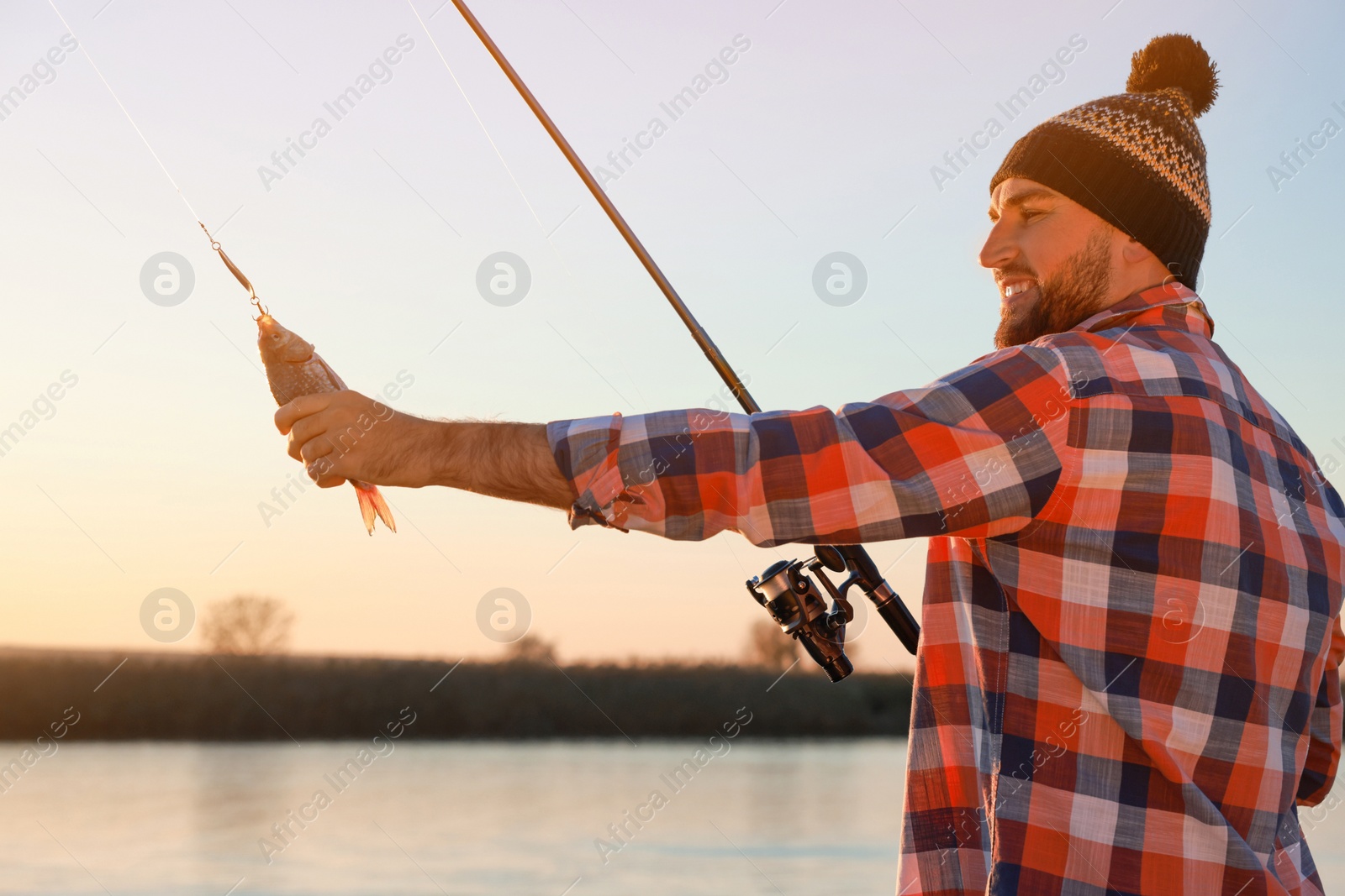 Photo of Fisherman with rod and caught fish at riverside