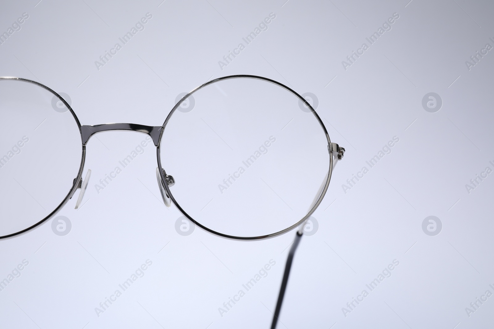 Photo of Stylish pair of glasses with metal frame on light grey background, closeup