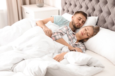 Young couple sleeping together in bed at home