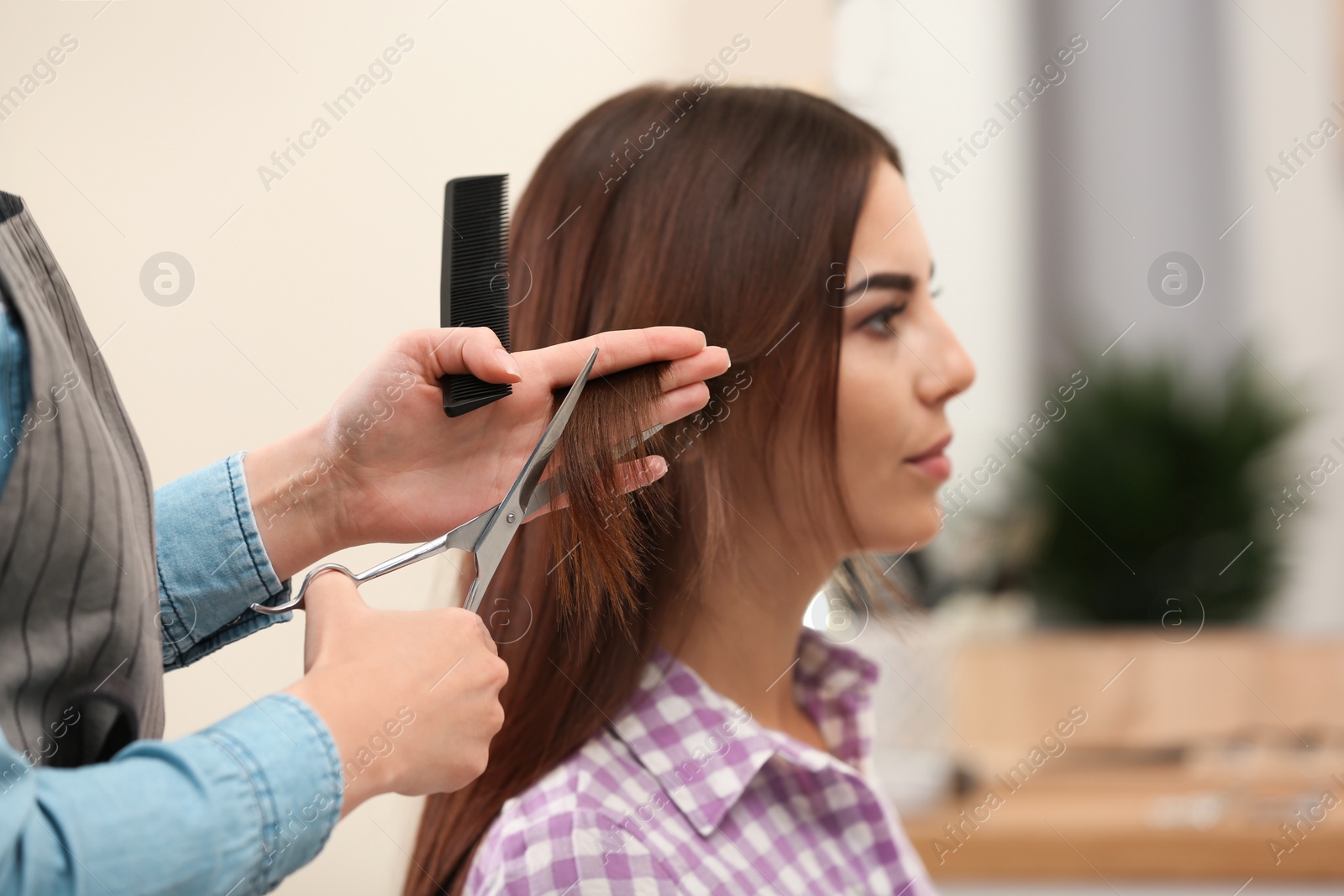 Photo of Barber making stylish haircut with professional scissors in beauty salon