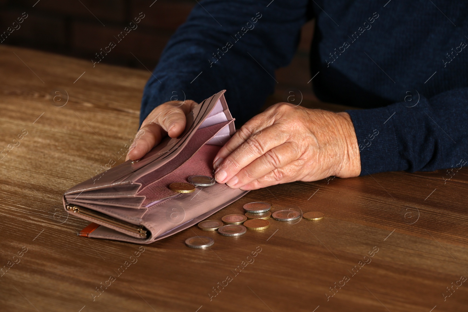 Photo of Poor elderly woman counting coins at table, focus on hands