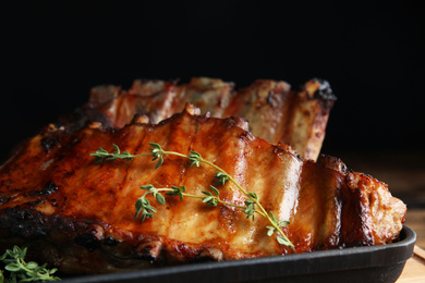 Tasty grilled ribs with thyme on table, closeup