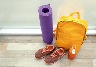 Photo of Sports bag and gym equipment on wooden floor near window