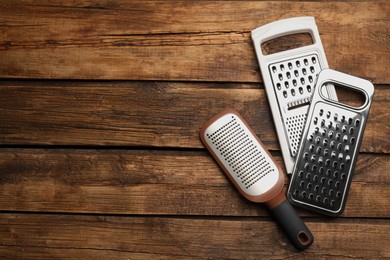 Photo of Different modern graters on wooden table, flat lay. Space for text