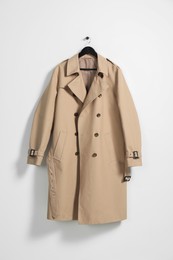 Photo of Hanger with beige trench coat on white wall