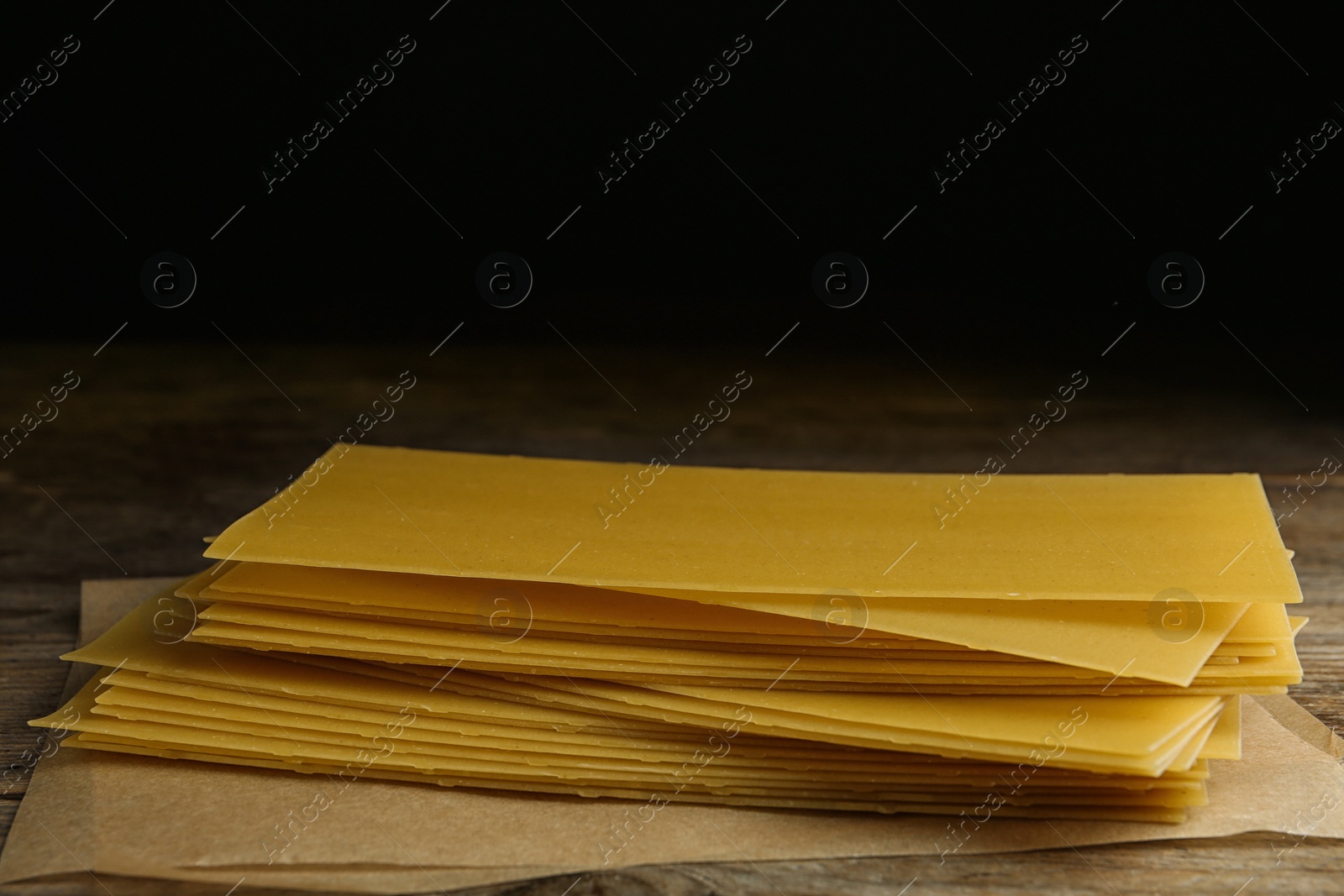 Photo of Uncooked lasagna sheets on wooden table. Italian cuisine