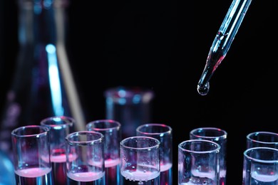 Dripping reagent into test tube on black background, closeup. Laboratory analysis