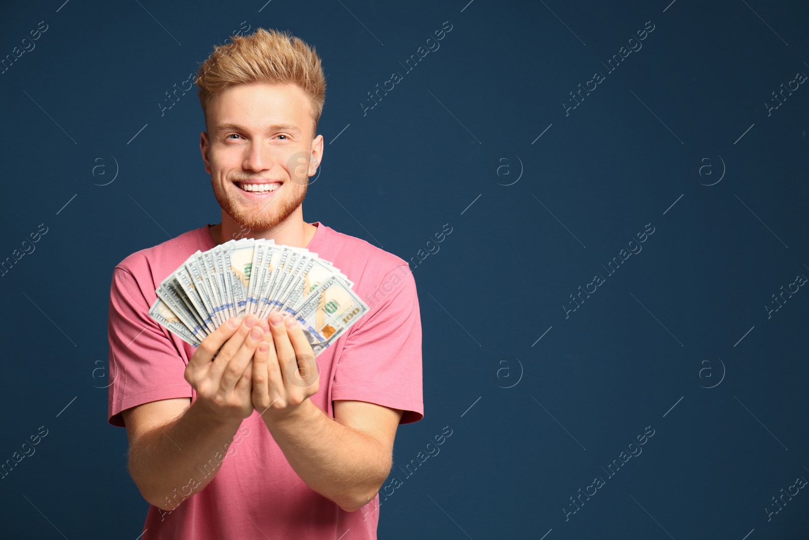 Photo of Portrait of happy lottery winner with money fan on blue background