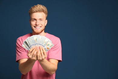 Portrait of happy lottery winner with money fan on blue background